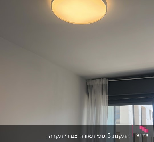מנורת תקרה דולקת בחדר עם חלון ווילון